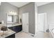 Bright, gray bathroom with single vanity, large mirror, and adjacent tub room at 3815 Harrison Crossing Ln, Greenwood, IN 46142