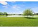 Scenic backyard with a sprawling lawn, a mature tree, and a picturesque view of the pond and surrounding residences at 4659 W Otway Ln, New Palestine, IN 46163