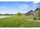 Beautifully landscaped backyard with lush lawn, patio area, and serene views of the pond and neighboring homes at 4659 W Otway Ln, New Palestine, IN 46163