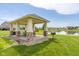 Picturesque community pavilion with stone pillars, picnic table, and barbecue, nestled by a tranquil pond at 4659 W Otway Ln, New Palestine, IN 46163