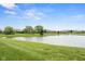 Community pond surrounded by lush greenery and neighboring homes, creating a serene and scenic environment at 4659 W Otway Ln, New Palestine, IN 46163