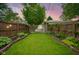 Well-maintained backyard features a green lawn, landscaping, and a wooden fence at 5225 E St Clair St, Indianapolis, IN 46219