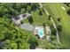 Gorgeous aerial view of a backyard oasis with swimming pool, tennis court, and lush greenery surrounded by nature at 6230 E 56Th St, Indianapolis, IN 46226