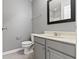 Bathroom with a gray vanity, white sink, black framed mirror, and gray walls at 6916 Havenmoor Pl, Indianapolis, IN 46250