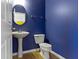 Stylish powder room with a sleek pedestal sink, toilet, and bold blue walls at 6916 Havenmoor Pl, Indianapolis, IN 46250