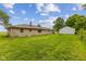 Spacious backyard with stone house and garage, lush green grass, mature trees, and a fire pit at 6925 W State Road 128, Frankton, IN 46044