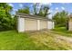 Two-car detached garage with white siding and two beige garage doors and a green lawn in front at 6925 W State Road 128, Frankton, IN 46044