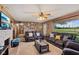 Spacious living room featuring leather furniture, ceiling fan, stone fireplace, and large window at 6925 W State Road 128, Frankton, IN 46044