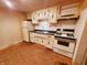 A cozy kitchen shows cream-colored cabinets, white appliances, and a dark countertop at 704 E Perry St, Indianapolis, IN 46227