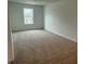 An empty carpeted bedroom with one window and white walls shows spacious potential at 7605 Big Bend Blvd, Camby, IN 46113
