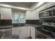 Well-lit kitchen features granite counters, stainless appliances, black backsplash, and bright window at 858 Cedar Wood, Carmel, IN 46032