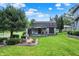 Charming backyard with lush lawn, mature tree, fountain feature, and cozy porch at 10036 E Troy Ave, Indianapolis, IN 46239