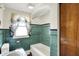 Bathroom featuring vintage green tile walls, a classic vanity, and a window adorned with decorative curtains at 10036 E Troy Ave, Indianapolis, IN 46239
