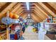 Spacious attic with exposed wooden beams, filled with decorations, storage items, and a fan at 12082 Old Stone Dr, Indianapolis, IN 46236