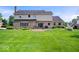 Back exterior view of the home showcasing the nicely manicured lawn and stone patio at 12082 Old Stone Dr, Indianapolis, IN 46236