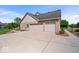 Triple garage with large driveway, brick exterior, and mature landscaping surrounding the building at 12082 Old Stone Dr, Indianapolis, IN 46236