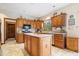 Well-lit kitchen featuring an island, wood cabinetry, stainless steel appliances, and tile backsplash at 12082 Old Stone Dr, Indianapolis, IN 46236
