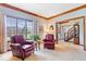 Inviting living room featuring a window, two leather chairs, wood trim and a view into the foyer at 12082 Old Stone Dr, Indianapolis, IN 46236