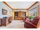 Cozy living room featuring a built in bookcase, two reading chairs, a wooden desk, and a large window at 12082 Old Stone Dr, Indianapolis, IN 46236