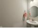 Small bathroom with neutral walls, round mirror, pedestal sink, and a hand towel at 1270 Shaw Ln, Shelbyville, IN 46176
