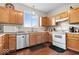 Practical kitchen with wood cabinets, white appliances, and a large window for natural light at 12832 Broncos Dr, Fishers, IN 46037