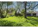 Lush green backyard with mature trees and glimpses of neighboring properties at 1515 S Emerson Ave, Indianapolis, IN 46203