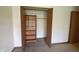 An open closet with shelves and bi-fold doors is located inside this carpeted bedroom at 1652 Sweetwater Ln, Greenfield, IN 46140