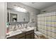 Well-lit bathroom features double sinks, modern fixtures, and a shower with a colorful striped curtain at 17002 Folly Brook Rd, Noblesville, IN 46060