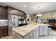 Open-concept kitchen with island, stainless appliances, dark cabinets, and view of staircase at 17002 Folly Brook Rd, Noblesville, IN 46060