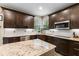Modern kitchen with stainless steel appliances, dark wood cabinetry, granite countertops, and tiled backsplash at 17002 Folly Brook Rd, Noblesville, IN 46060