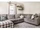 Comfortable living room with plush gray sectional, decorative shelves, and lots of natural light at 1747 S Irvington Ave, Indianapolis, IN 46203