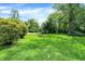 Lush backyard with trees, gravel driveway, and a fire pit, offering a tranquil outdoor space at 2150 S Emerson Ave, Indianapolis, IN 46203