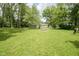 Wide backyard featuring a fire pit, mature trees, and lush green space, perfect for outdoor activities at 2807 Westleigh Dr, Indianapolis, IN 46268