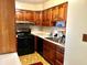Functional kitchen with wooden cabinets, black appliances, and tiled backsplash for easy cleaning at 3633 Tiffany Dr, Indianapolis, IN 46226