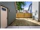 View of the backyard featuring a wooden fence, grass, and a side door at 39 N Walcott St, Indianapolis, IN 46201