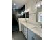 A modern bathroom features double sinks with quartz countertops, grey cabinets, and a sleek, glass-enclosed shower at 39 N Walcott St, Indianapolis, IN 46201