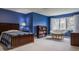 Blue bedroom with a comfy papasan chair, large window, and a wooden bed frame at 4037 Oakleaf Dr, Zionsville, IN 46077