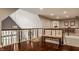 Upstairs landing with hardwood floors, wood railing, and a cozy bench with ornate pillows at 4037 Oakleaf Dr, Zionsville, IN 46077