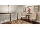 Hallway sitting area featuring hardwood floors, ornate railings, a small table, and tufted chairs at 4037 Oakleaf Dr, Zionsville, IN 46077