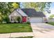 Charming brick home features a bright red front door and well-manicured lawn, and an attached two-car garage at 410 Wood Hollow Ct, Westfield, IN 46074