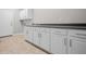 This is a laundry room with white cabinets and a sink with black countertops and a tile floor and a white door at 4368 W Eagle Trce, New Palestine, IN 46163