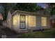A side view of the home with gray siding, a black security door, trimmed bushes, and well-lit exterior at 4809 Allisonville Rd, Indianapolis, IN 46205