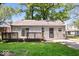 A side view of the house with gray siding, a small wooden deck, and green lawn at 4809 Allisonville Rd, Indianapolis, IN 46205
