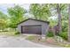 A detached one car garage with a dark brown door has a small garden with corrugated metal planters to the side at 584 S 10Th St, Noblesville, IN 46060