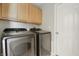 Efficient laundry room with wood cabinets and modern washer and dryer units at 608 Fisher Creek Dr, Indianapolis, IN 46239