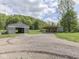 Wide driveway leading to a metal garage and a house with covered parking, surrounded by lush greenery at 6091 Mt Moriah Rd, Nineveh, IN 46164