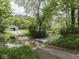 Scenic view of a property entrance with a stream, leading to a house and garage surrounded by lush greenery at 6091 Mt Moriah Rd, Nineveh, IN 46164