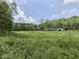 Expansive green field with a metal garage and house in the background, offering ample space for outdoor activities at 6091 Mt Moriah Rd, Nineveh, IN 46164