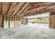 The garage interior has an open door, exposed rafters, shelving, and a cracked concrete floor at 6110 Orinoco Ave, Indianapolis, IN 46227