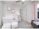 Welcoming Bedroom with plush carpet, ceiling fan, open closet, rocker, and a white crib with flower decor at 6833 Jacone Dr, Brownsburg, IN 46112
